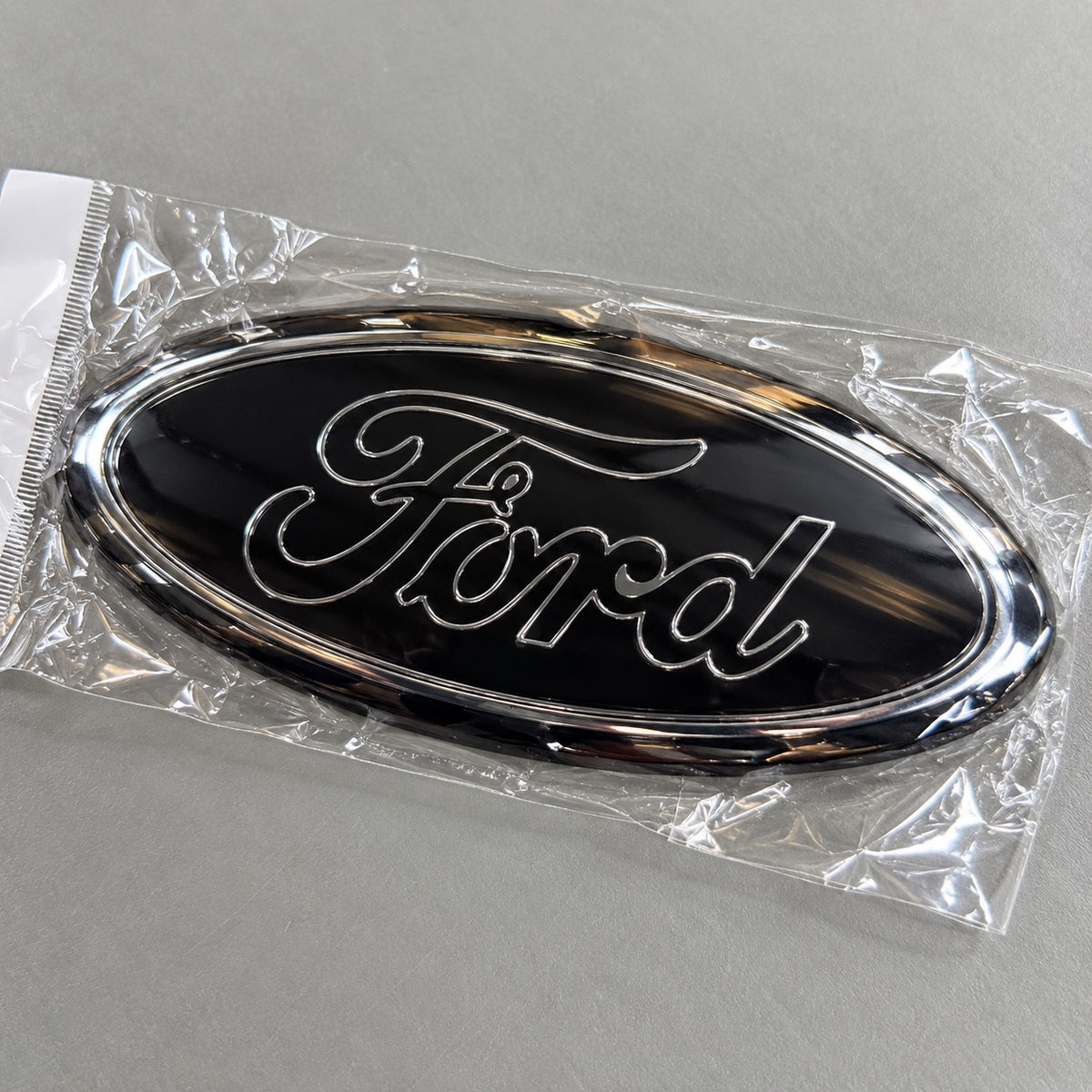 Black and chrome-effect aftermarket Ford oval badge in packaging
