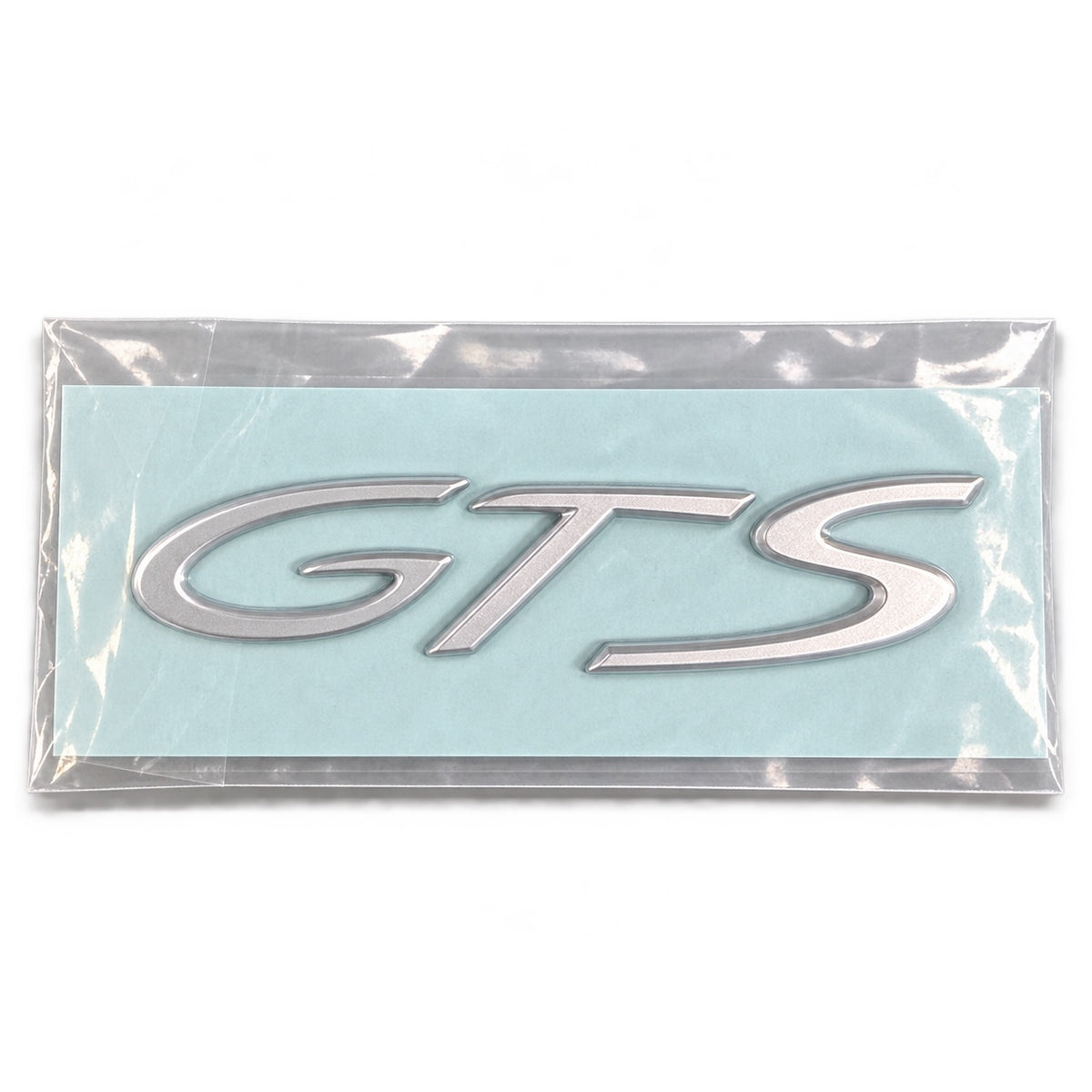 Silver-coloured aftermarket GTS badge set in protective packaging