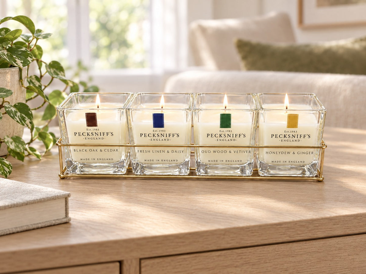 Four-candle caddy set lit on a living-room console (styled image)