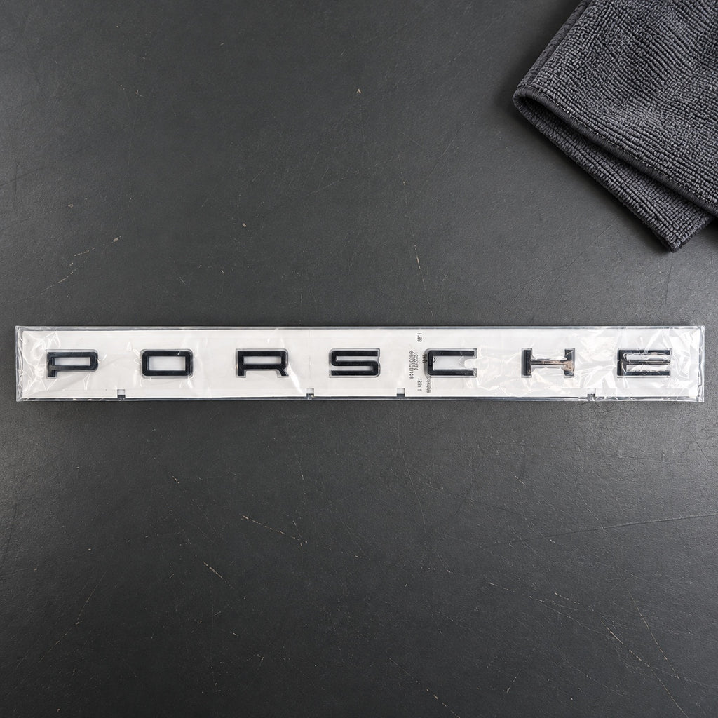 Black aftermarket Porsche seven-letter badge set in packaging