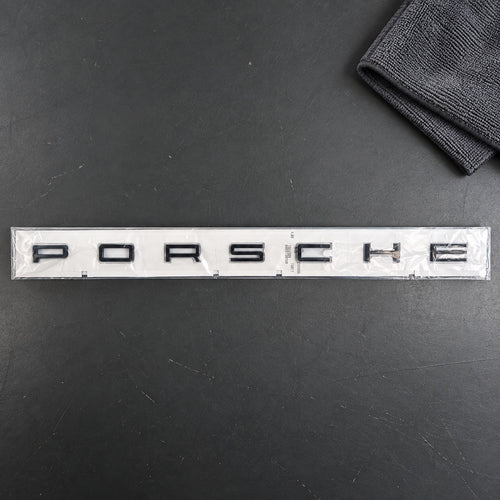 Black aftermarket Porsche seven-letter badge set in packaging