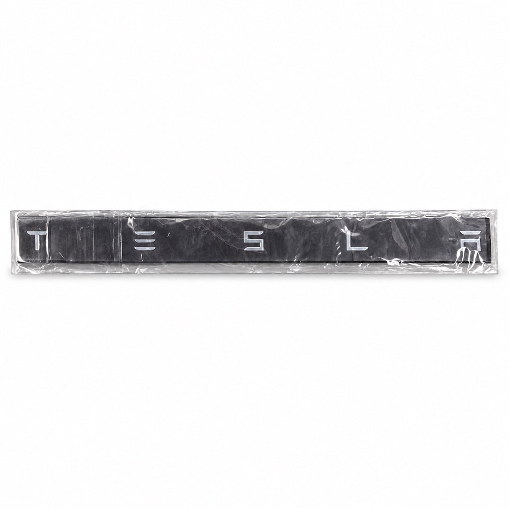 Silver-coloured aftermarket Tesla lettering set in protective packaging
