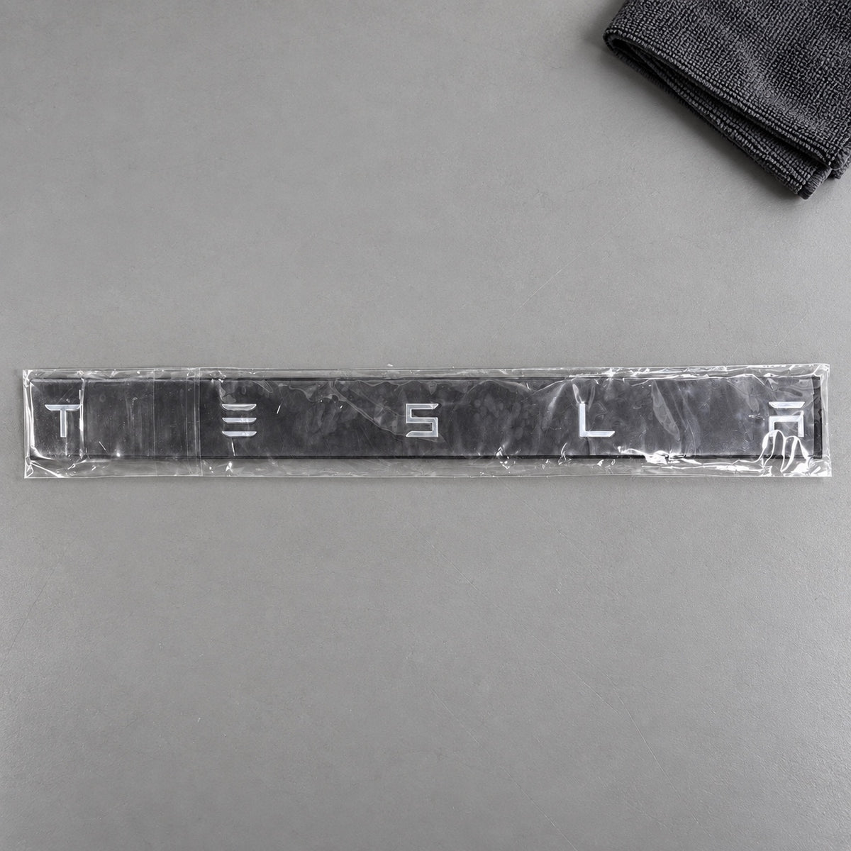 Silver-coloured aftermarket Tesla lettering set in protective packaging