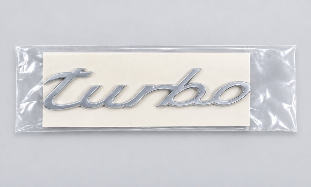 Silver-coloured aftermarket turbo script badge in protective packaging